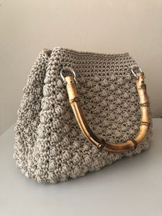 a crocheted purse with bamboo handles on a white countertop next to a wall