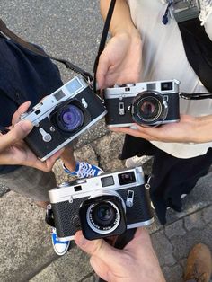 three people holding old cameras in their hands