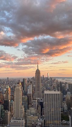 the city skyline is shown at sunset with clouds in the sky and skyscrapers on either side