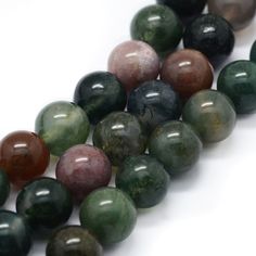 multicolored marble beads are lined up on a white surface, with one bead in the middle