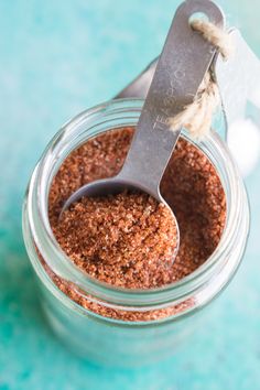 a spoon in a jar filled with ground cinnamon on top of a blue tablecloth