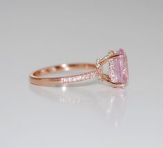 a pink tourmaline and diamond ring on a white surface