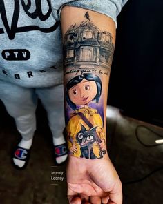 a woman's arm with a cartoon character tattoo on her left wrist and an image of a cat