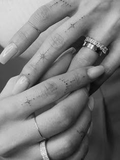 two people holding hands with tattoos on their fingers