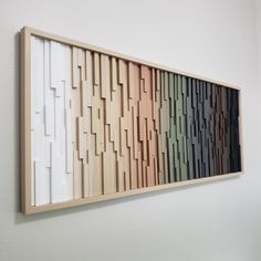 an art piece hanging on the wall with different colors and shapes in it's wood frame