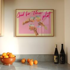 a bowl of oranges sitting on top of a kitchen counter next to bottles of wine