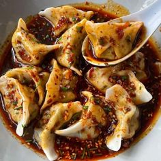 a white bowl filled with dumplings covered in sauce