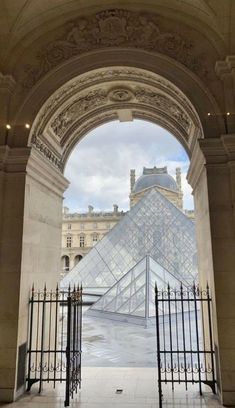 an arch leading into a building with a glass pyramid in the background