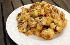 a white plate topped with cauliflower on top of a wooden table