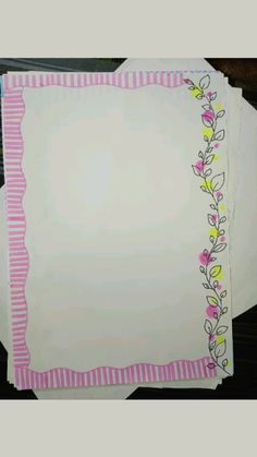 two blank papers with pink and green trims on top of each other, sitting next to each other