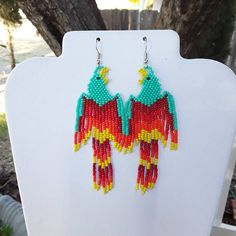 the beaded bird earrings are hanging from hooks on a white mannequin stand