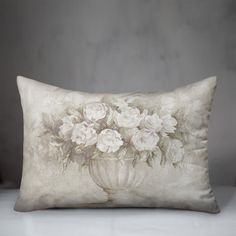 a pillow with white flowers on it sitting on a table next to a planter