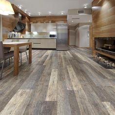 a kitchen with wood flooring and an oven in the center, next to a dining room table