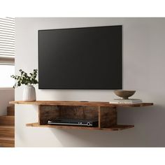 a flat screen tv mounted to the side of a wooden shelf next to a vase