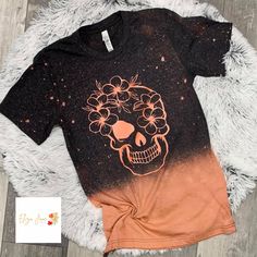 a t - shirt with a skull and flowers on it sitting on top of a rug