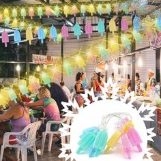 people are sitting at tables with colorful lights hanging from the ceiling and decorations above them