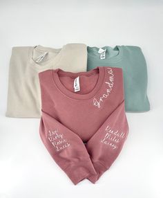 three sweaters with the words grandma written on them in white, pink, and blue