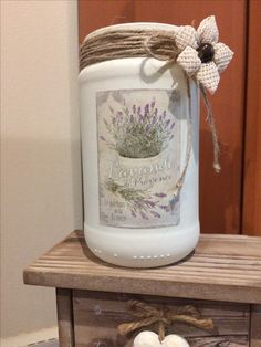 a jar sitting on top of a wooden table next to two cotton balls and twine