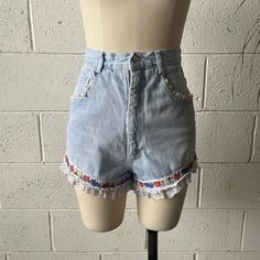 These 1990's vintage Extra Femme shorts are made from a light washed, cotton denim and white, nylon lace. Features a high waisted fit with floral ribbon around either leg and white, ruffled lace trim. Zips in front to a single button closure at the waist. A couple small tears in the lace that aren't noticeable but reflected in price. In overall excellent vintage condition with only minimal signs of wash and wear.   Marked a size 7, see below for measurements 25" waist 36" hips 13" rise 3" inseam Vintage Denim Jean Shorts For Summer, Vintage Jeans With Frayed Hem For Spring, High Waist Cotton Bottoms With Lace Trim, High-waist Cotton Bottoms With Lace Trim, Spring Vintage Jeans With Frayed Hem, Vintage White Cotton Jean Shorts, Vintage Denim Blue Jeans For Summer, White Cotton Vintage Jean Shorts, Vintage White Jean Shorts For Spring