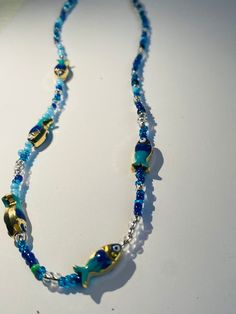 hand made blue silver and gold choker necklace with five blue and gold fish. handmade with care and perfect for a gift for that special person Blue Beads For Festivals, Blue Metal Jewelry With Lobster Clasp, Blue Beads With Gold Details As A Gift, Metal Necklaces With Spacer Beads For Gift, Blue Necklace With Lobster Clasp For Party, Metal Necklace With Spacer Beads For Gift, Silver Spacer Beads Choker For Gift, Blue And Gold Beads For Jewelry Making, Handmade Blue Metal Necklace