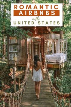 a woman walking across a wooden bridge in the middle of a forest with a tree house on top