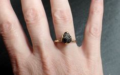 a woman's hand with a ring on it that has a black stone in the middle