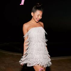 a woman in a white dress is smiling and posing for the camera with her pink shoes