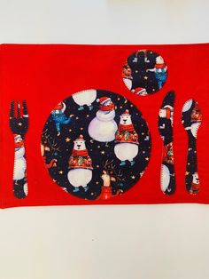 a red place mat with snowmen on it and silverware in front of them