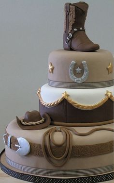 a three tiered cake with cowboy boots on top and other items around the bottom