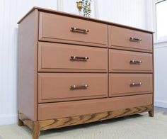 a large brown dresser sitting on top of a carpeted floor next to a window