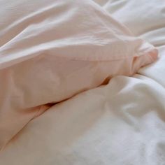 an unmade bed with white sheets and pillows