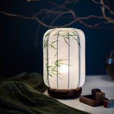 a lamp that is on top of a table next to some other items and a tree branch