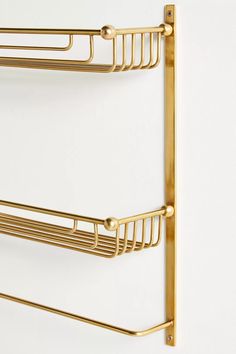 two gold metal shelves on the wall next to each other, one has a towel rack