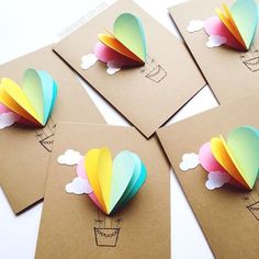 four different colored paper hot air balloons on brown envelopes