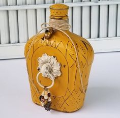 a yellow bottle with a ring hanging from it's side on a white surface