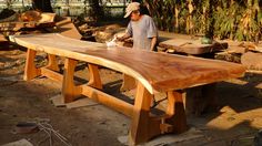 a man sanding on top of a wooden bench