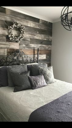 a bed with pillows and blankets on top of it in front of a wooden wall