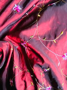 the fabric is red with pink flowers on it and gold trimming around the edges