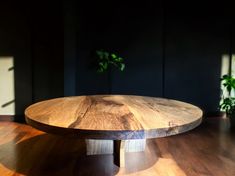 a wooden table sitting on top of a hard wood floor next to a potted plant