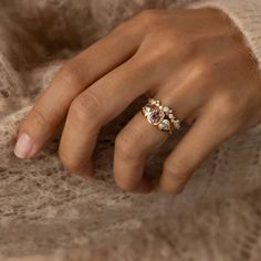 a woman's hand wearing a gold ring with three stones on the middle finger