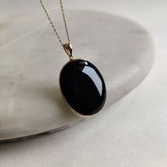 ITEM DESCRIPTION: >>The pendant is made from Solid 14K Yellow Gold. Gemstone used is absolutely natural and ethically sourced. >>Natural Black Onyx in cabochon cut and Oval shape with bezel setting is studded on it with utmost precision. >>This is a minimalist design and is absolutely hassle-free and everyday jewelry. Gem: Black Onyx Gem size: 27×22 mm Gold purity: 14K (58.33% approx.) Gold weight: 0.90 grams Gross weight: 6.13 grams Gold purity: 14K (58.33% approx.) The Gold purity is guarantee Timeless Black Pendant Necklace, Timeless Black Enamel Necklace, Timeless Onyx Gemstone Jewelry, Formal Onyx Oval Necklace, Black Onyx Timeless Jewelry, Black Enamel 14k Gold Necklace, Black Enamel Oval Necklace As Gift, Black 14k Gold Pendant Jewelry, Black Enamel Oval Necklace For Gift