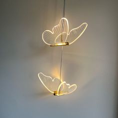 two lights that look like butterflies are hanging from the ceiling in front of a white wall