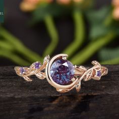 a ring with an oval shaped purple stone surrounded by leaves