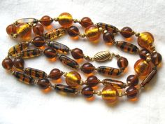 This is a gorgeous 32 inches long vintage tiger stripe beaded necklace. It is hand strung and painstakingly knotted between the gold tone end caps of each bead. This necklace was made in the 1960s or 1970s. The scalloped gold tone clasp is fish hook style.    There are four different kinds of beads in the strand: There are lozenge shaped honey color beads with black stripes (my favorites). They remind me of tiger stripes. There are also large 12mm round beads with shimmering, mottled gold tone i Celluloid Jewelry, Vintage Tiger, Vintage Jewelry Art, Tiger Stripes, Amber Jewelry, Art Deco Jewelry, Etsy Jewelry, Vintage Costume Jewelry, Vintage Jewellery