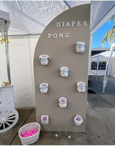 there are many cups and bowls on the display wall in front of the tent with pink balls