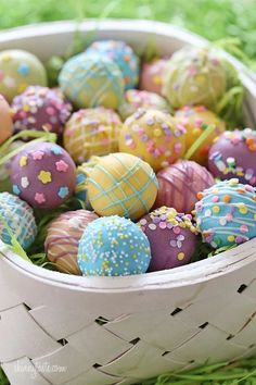 a basket full of decorated easter eggs on the grass