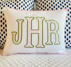 a white pillow with the letter jhr on it sitting on top of a bed