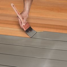 a person holding a brush on top of a wooden floor