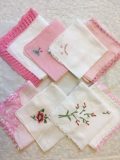 several different types of handkerchiefs are laid out on a white tablecloth with pink trim