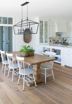 a wooden table surrounded by white chairs in a kitchen